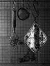 Old italian vintage kitchen utensils. Potholder, strainer and whisk hanging on racks on kitchen wall