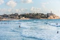 Old Jaffa city, old port and coastal line of Tel Aviv under sunset and lots of tourists are swimming and surfing at the