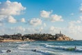Old Jaffa city, old port and coastal line of Tel Aviv under sunset and lots of tourists are swimming and surfing at the