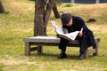 Old Japanese Man sits in park and reads the daily Newspaper Royalty Free Stock Photo