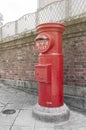 Old Japanese postbox stands beside a street in front of brick wall in a city of Japan with Japanese language translated as Post