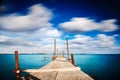 Old jetty walkway pier on the blue sea on long day exposure. Royalty Free Stock Photo