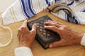 Old Jewish man hands holding a Prayer book, praying, next to tallit and shofar horn. Jewish traditional symbols. Rosh hashanah Royalty Free Stock Photo