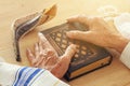 Old Jewish man hands holding a Prayer book, praying, next to tallit and shofar horn. Jewish traditional symbols. Rosh hashanah