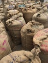 Old jute sacks or bags filled with food grains stored in a warehouse.