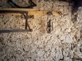 Old kerosene lamp and rusty tools hang on a stone wall