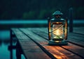 Old kerosene lantern with warm yellow light on a bridge by a lake in the evening. Burning lantern on a stone in the Royalty Free Stock Photo