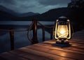 Old kerosene lantern with warm yellow light on a bridge by a lake in the evening. Burning lantern on a stone in the Royalty Free Stock Photo