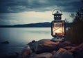 Old kerosene lantern with warm yellow light on a bridge by a lake in the evening. Burning lantern on a stone in the Royalty Free Stock Photo