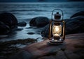 Old kerosene lantern with warm yellow light on a bridge by a lake in the evening. Burning lantern on a stone in the Royalty Free Stock Photo