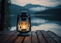 Old kerosene lantern with warm yellow light on a bridge by a lake in the evening. Burning lantern on a stone in the Royalty Free Stock Photo