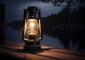 Old kerosene lantern with warm yellow light on a bridge by a lake in the evening. Burning lantern on a stone in the Royalty Free Stock Photo
