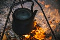 Old kettle is burning at the stake, tourists boil water on the fire. Fire campfire and cooking in the campaign Royalty Free Stock Photo
