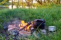 An old kettle with a cup stands on a fire in nature