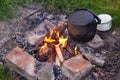 An old kettle with a cup stands on a fire in nature