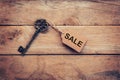 Old key with tag and text sale on wooden