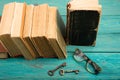 Old keys, glasses and stack of antique books on blue wooden desk Royalty Free Stock Photo