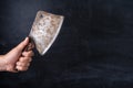 Old kitchen cleaver in the chef`s hand on a dark background Royalty Free Stock Photo