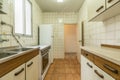 Old kitchen with old furniture in poor condition, white fridge, vintage tiles and aluminum window with translucent glass