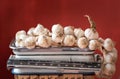 An old kitchen scale stands against a red background with space for text. On the scales is a braid with white garlic Royalty Free Stock Photo