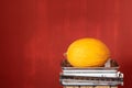 An old kitchen scale stands against a red background with space for text. A yellow honeydew melon lies on the scales Royalty Free Stock Photo
