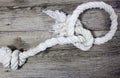 Old knoted rope lays on wooden background.