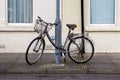 An old ladies bike with a basket chained to a lamppost in the street Royalty Free Stock Photo