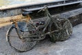 Old ladies bike pulled out of the river, moss and many stones sticking to the bike, totally rusted and broken, service wallet and