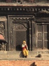 Old lady in Bhaktapur Nepal sitting on a ledge near the palace