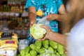 An old lady hands over a piece of white cabbage to a vendor. Buying vegetables at a small market shop Royalty Free Stock Photo