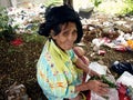 An old lady hunts or scavenges for recyclable materials in a pile of trash in an abandoned lot.