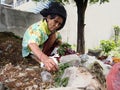 An old lady hunts or scavenges for recyclable materials in a pile of trash in an abandoned lot.