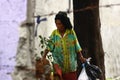 An old lady hunts or scavenges for recyclable materials in a pile of trash in an abandoned lot.