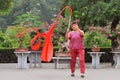 Old lady practices traditional gymnastics with red ribbon in Jingshan Park in Beijing, China