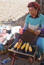 Old lady preparing grilled corn