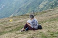 Ticino, Switzerland - August 5, 2019: Old lady read magazine with cigarette on top of Monte Tamaro