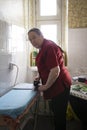 Old lady in the red blouse ironing a towel at home Royalty Free Stock Photo