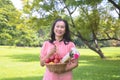 The old lady relax in the park.She is walking and holding the fruit Basket and bouquet of flowers.