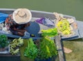 Old lady stay on her boat and sell some local vegetable and a bunch of banana, near a pier in Thailand.