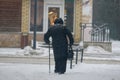 An old lady with stick walking, during snowfall
