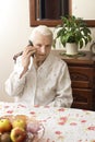 The old lady talking on a cell phone while sitting at a table in the living room. Royalty Free Stock Photo