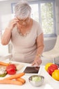 Old lady using tablet in kitchen Royalty Free Stock Photo