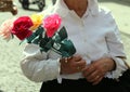 old lady with white blouse walks with a pack of four roses