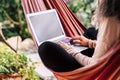 Old lady working on a computer laptop sitting on a coloured hammock - job and work everywhere with internet connection wifi - Royalty Free Stock Photo