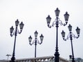 Old lampposts against the gray sky. Park lighting. Lanterns during the day
