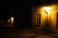 Old lanterns illuminating a dark alleyway medieval street at night in Prague, Czech Republic. Low key photo with brown yellow tone