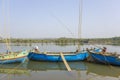 Old large fishing boats with engines anchored off the coast against the backdrop of a river and green trees on the shore