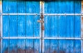 The old large wooden doors painted in blue and closed on the padlock. The blue gate on the lock. Wooden gates closeup Royalty Free Stock Photo
