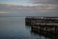 old large wooden pier stands on shore of lake, seaside in the evening at sunset in water Royalty Free Stock Photo