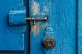 The old latch lock the blue wooden doors. An old round handle on the door. Parched boards. Village life Royalty Free Stock Photo
